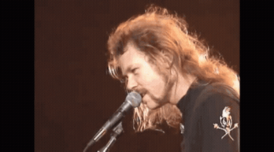 Man With Long Hair Singing Into Microphone GIF