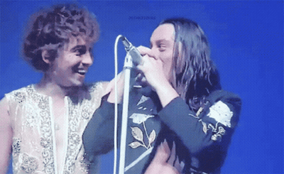 Man With Long Hair Singing Into Microphone GIF