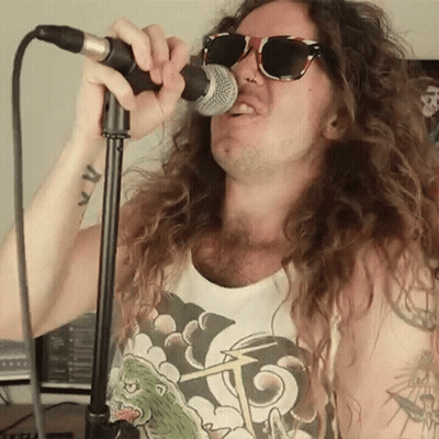 Man With Long Hair Singing Into Microphone GIF
