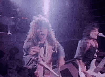 Man With Long Hair Singing Into Microphone While Man Plays Guitar GIF