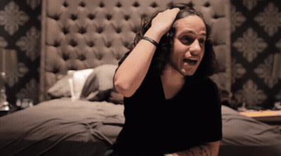 Man With Long Hair Sitting On Bed GIF