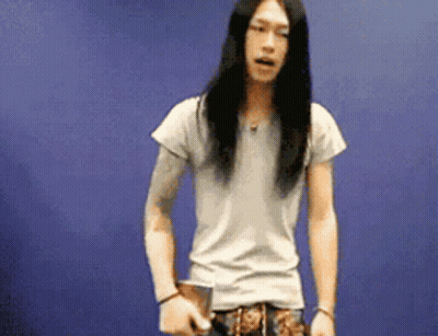 Man With Long Hair Standing In Front Of Blue Wall GIF