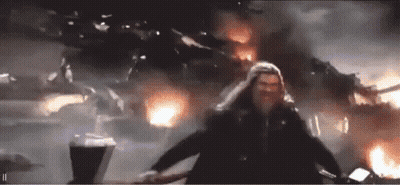 Man With Long Hair Standing In Front Of Fire And Building GIF