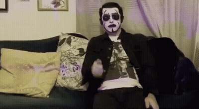 Man With Mask Sitting On Couch With Remote GIF