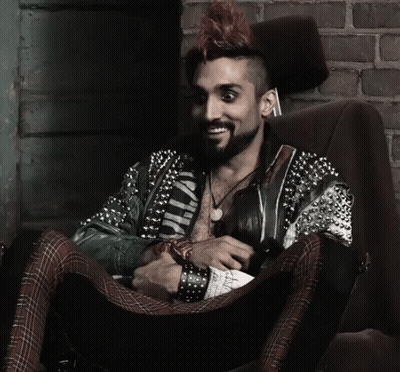 Man With Mohawk Sitting In Chair Wearing Wild Jacket GIF