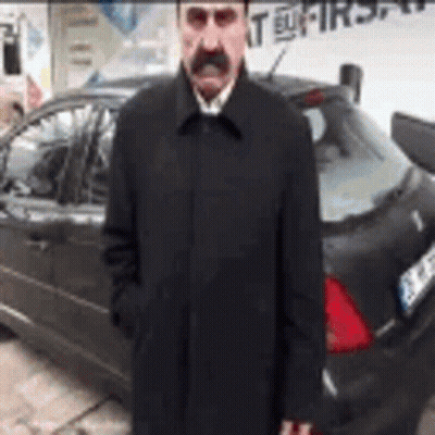 Man With Mustache And Coat Standing In Front Of Car GIF