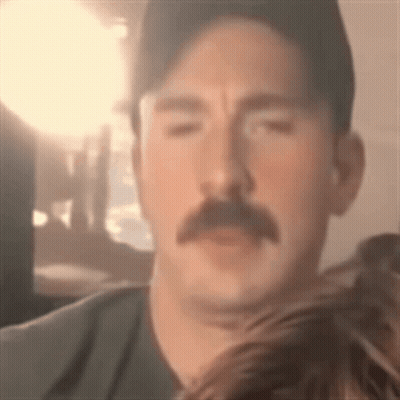 Hombre con bigote y sombrero mirando a la cámara GIF