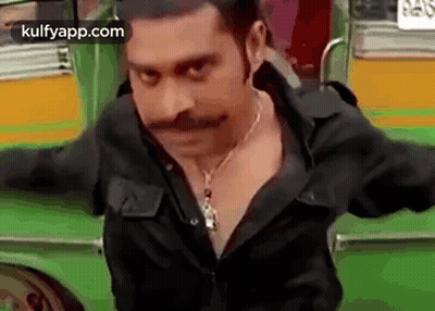 Man With Mustache And Necklace Standing Before Green Bus GIF