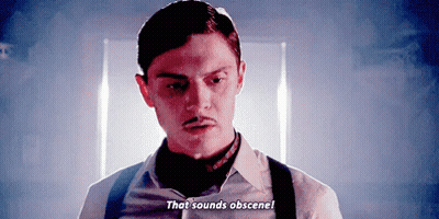 Man With Mustache And Suspenders Talking In Dark Room GIF