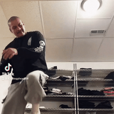 Man With Mustache Dancing In Front Of Rack Of Clothes GIF