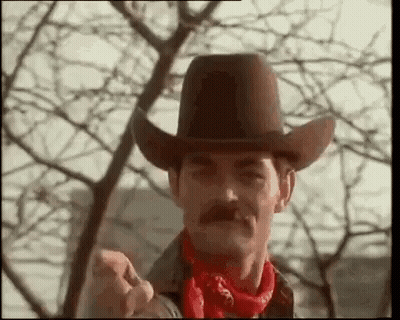 Man With Mustache In Cowboy Hat And Red Bandana Pointing At Camera GIF