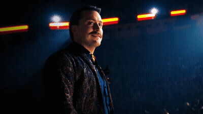 Man With Mustache In Front Of Crowd In Dark Room GIF