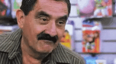 Man With Mustache Making Funny Face In Front Of Magazines GIF