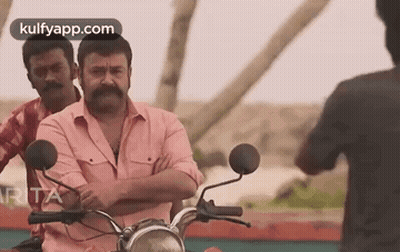 Man With Mustache Riding Motorcycle Beside Two Men GIF