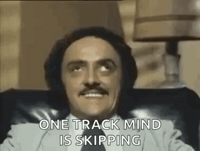 Man With Mustache Sitting In Chair Says One Track Mind Is Skipping GIF