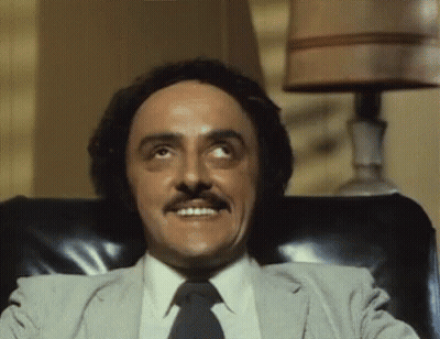 Man With Mustache Sitting In Chair Smiling GIF