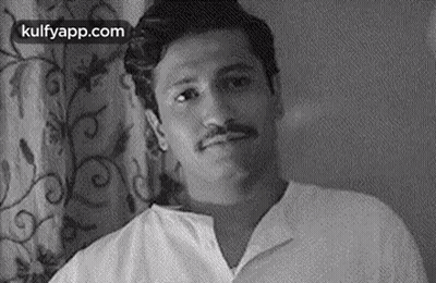 Man With Mustache Sitting In Front Of Curtain GIF