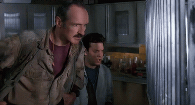 Man With Mustache Standing Beside Another Man Looking Out Window GIF