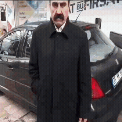 Man With Mustache Standing In Front Of Black Car License Plate 35 TK 88 GIF