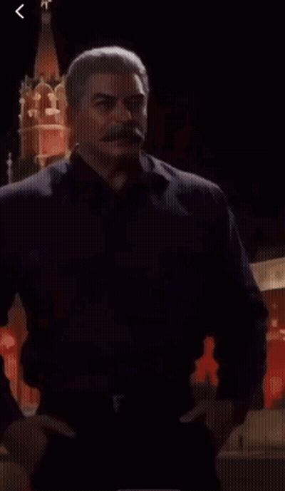 Man With Mustache Standing In Front Of Red Tower GIF
