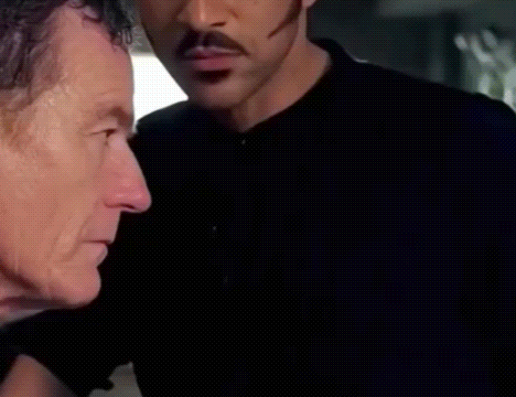 Man With Mustache Standing Next To Another Man In Dark Room GIF