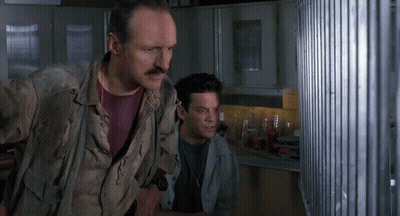 Man With Mustache Standing Next To Another Man Looking Out Window GIF