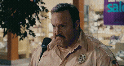 Man With Mustache Talking Into Microphone In Front Of Sale Sign GIF