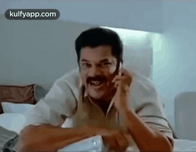 Man With Mustache Talking On Cell Phone In Bedroom GIF