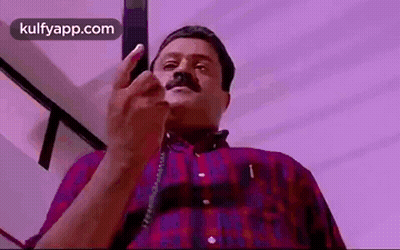 Man With Mustache Talking on Phone Pointing at Camera