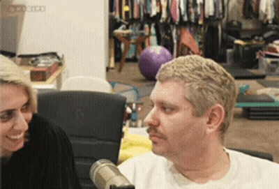 Man With Mustache Talking To Woman At Microphone GIF