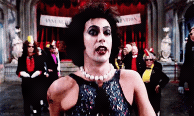 Man With Pearl Necklace Standing In Front Of Association Sign GIF