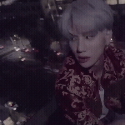 Man With Purple Hair And Red Jacket Sitting On Ledge GIF