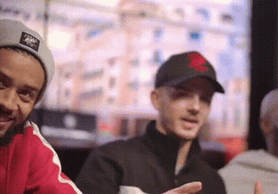 Man With Red Heart Hat Standing Next To Man GIF