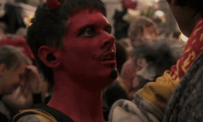 Man With Red Paint And Mustache Looks At Another Man GIF