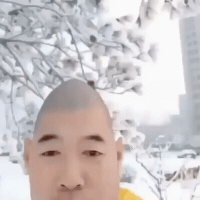 Man With Shaved Head Standing In Front Of Flowering Tree GIF