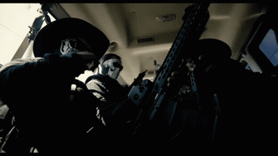 Man With Skull Mask Holding Gun In Dark Room GIF