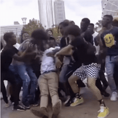 Man With Smiley Face On Back Surrounded By People GIF