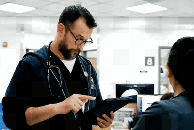 Man With Stethoscope Looking At Tablet While Woman Looks On GIF