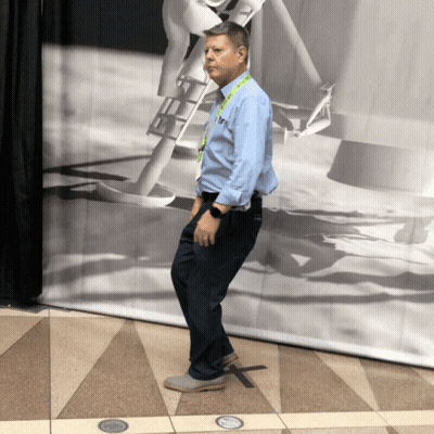 Man With T Lanyard In Front Of Black And White Picture GIF