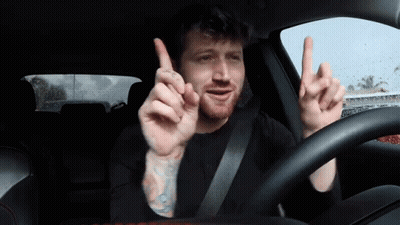 Man With Tattoo Driving Car Pointing Up GIF