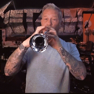 Man With Tattoos Playing Trumpet In Dark Room GIF