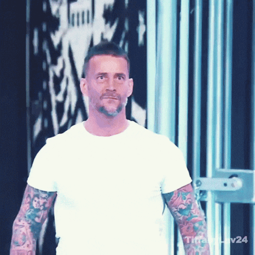 Man With Tattoos Wearing White T-Shirt In Front Of Wall With Number 24 GIF