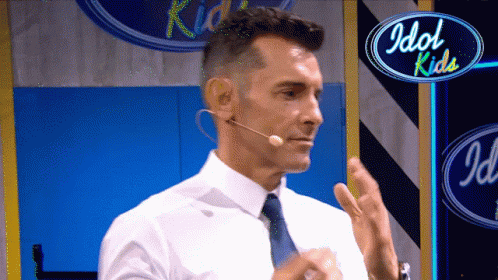 Man With Tie And Microphone In Front Of Idol Kids Sign GIF
