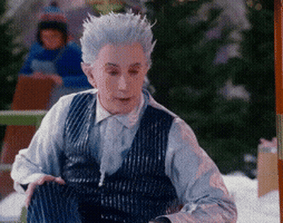 Man With White Hair And Blue Vest Sitting In Snow GIF