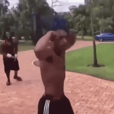 Man Without Shirt On Brick Walkway With Another Man Behind GIF