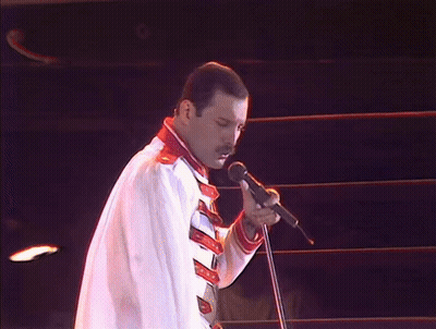 Man Without Shirt Singing Into Microphone Holding Flag GIF