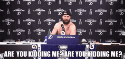 Man Without Shirt Sitting At Table In Front Of Champions Wall GIF