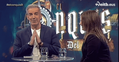 Man Woman At Table With El Conquistas9 Sign GIF