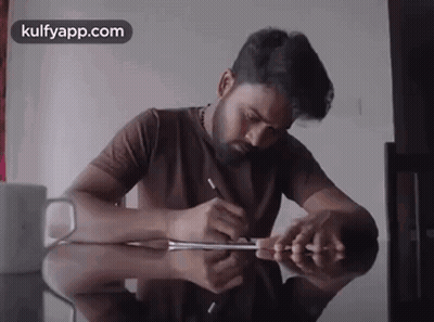 Man Writing At Table With Kulfyapp Logo GIF