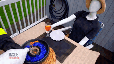 Mannequin At Table With Inside Edition Bottle GIF